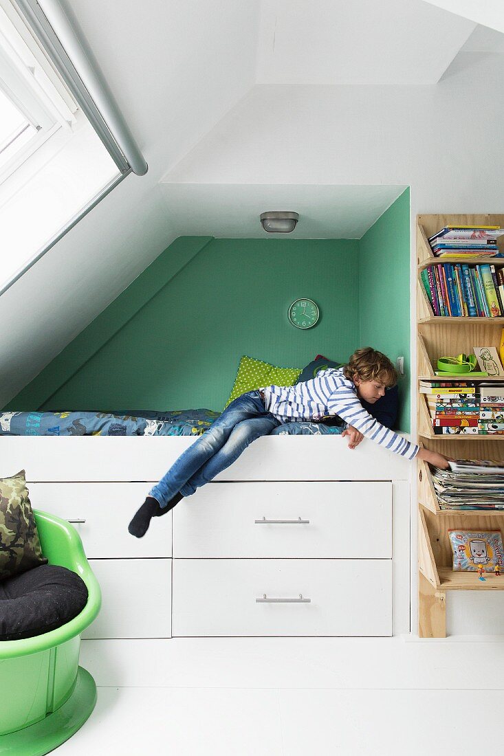 Jugendzimmer mit Dachschräge, Junge in grüner Bettnische mit eingebautem Schubladenschrank