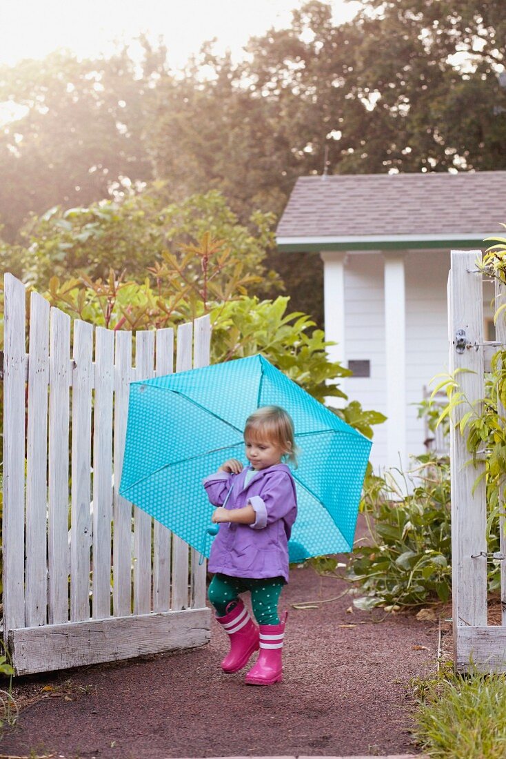 Kleines Mädchen mit blauem Regenschirm