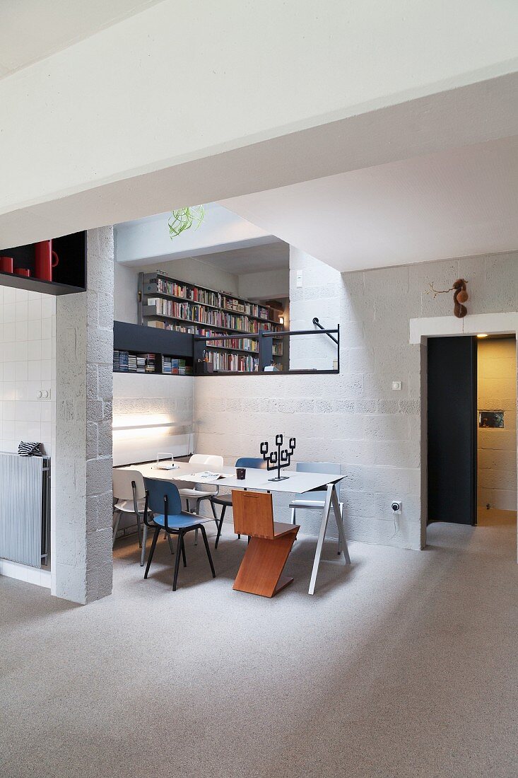 Dining area with Bauhaus chairs around table in open-plan interior with breeze block walls