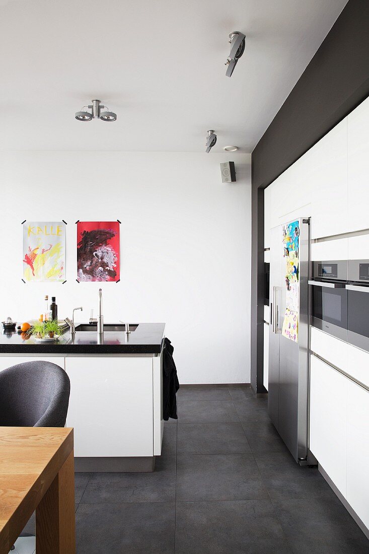 Modern, open-plan kitchen with free-standing counter and white fitted cupboards