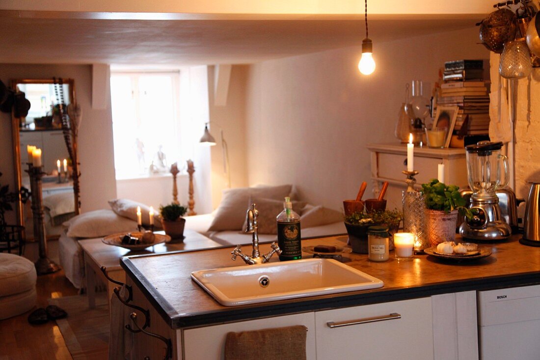 Blick über Küchentheke mit Kochutensilien in schlichten Wohnbereich, im Hintergrund gemütliche Polsterbänke