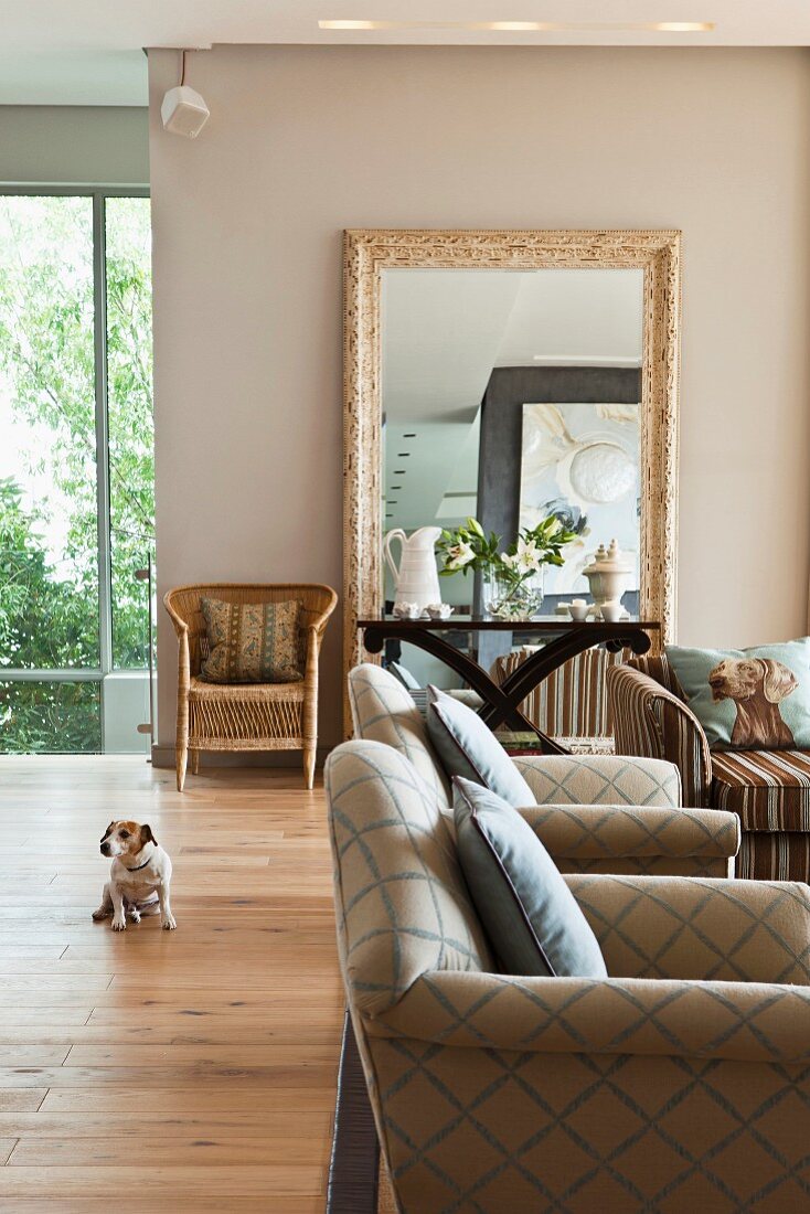 Wohnzimmer mit Polstermöbeln im Karo-Look, im Hintergrund Beistelltisch vor großem gerahmtem Standspiegel an beigefarbener Wand