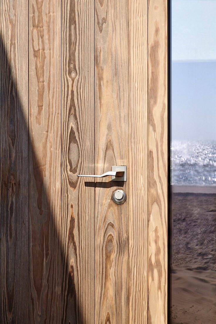 Holztür mit Designer-Türgriff, seitlich Glasausschnitt mit Reflexion vom Meer