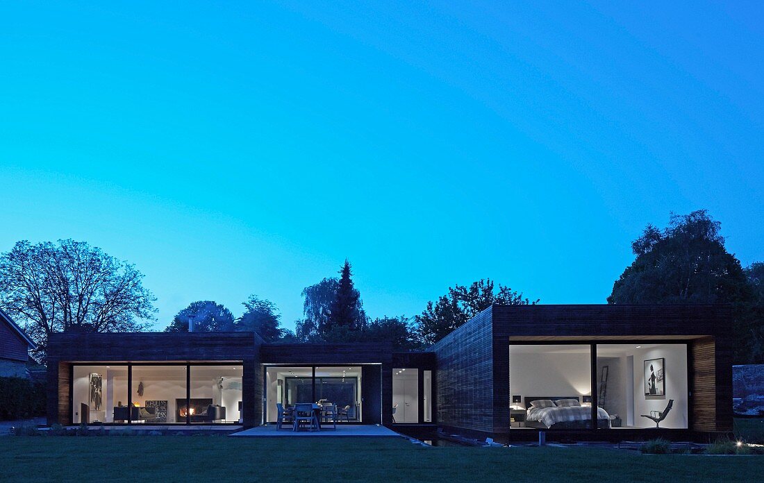Point 7, Winchester, United Kingdom. Architect: Dan Brill Architects, 2014. Exterior of contemporary house complex with illuminated interior at dusk