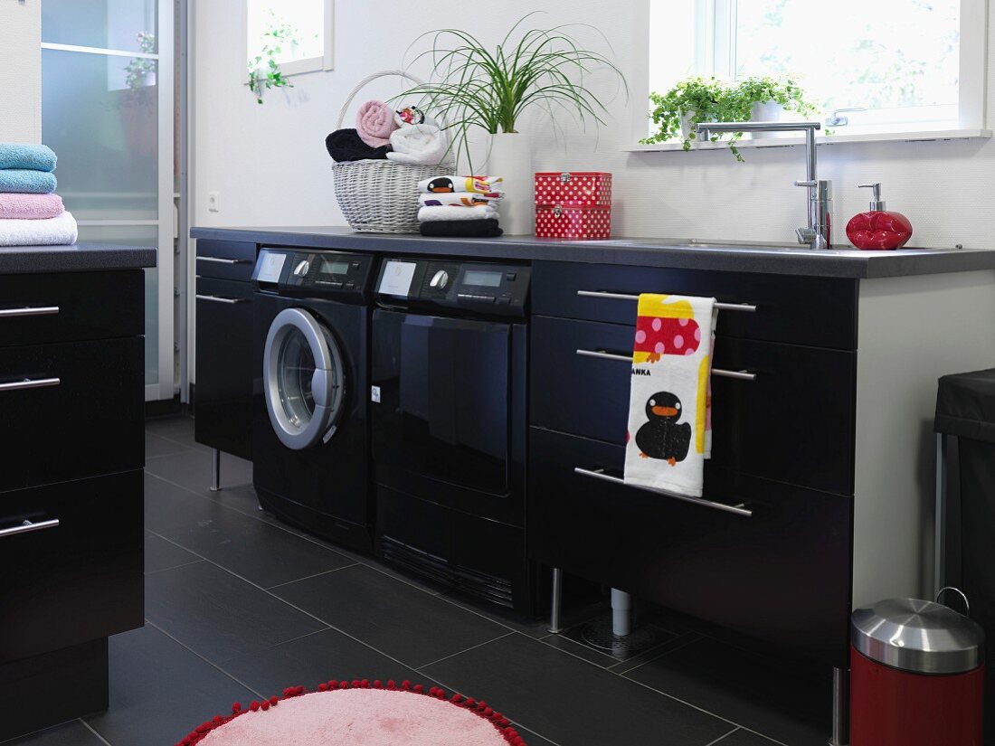 Modern laundry room with black appliances integrated into counter with black base units