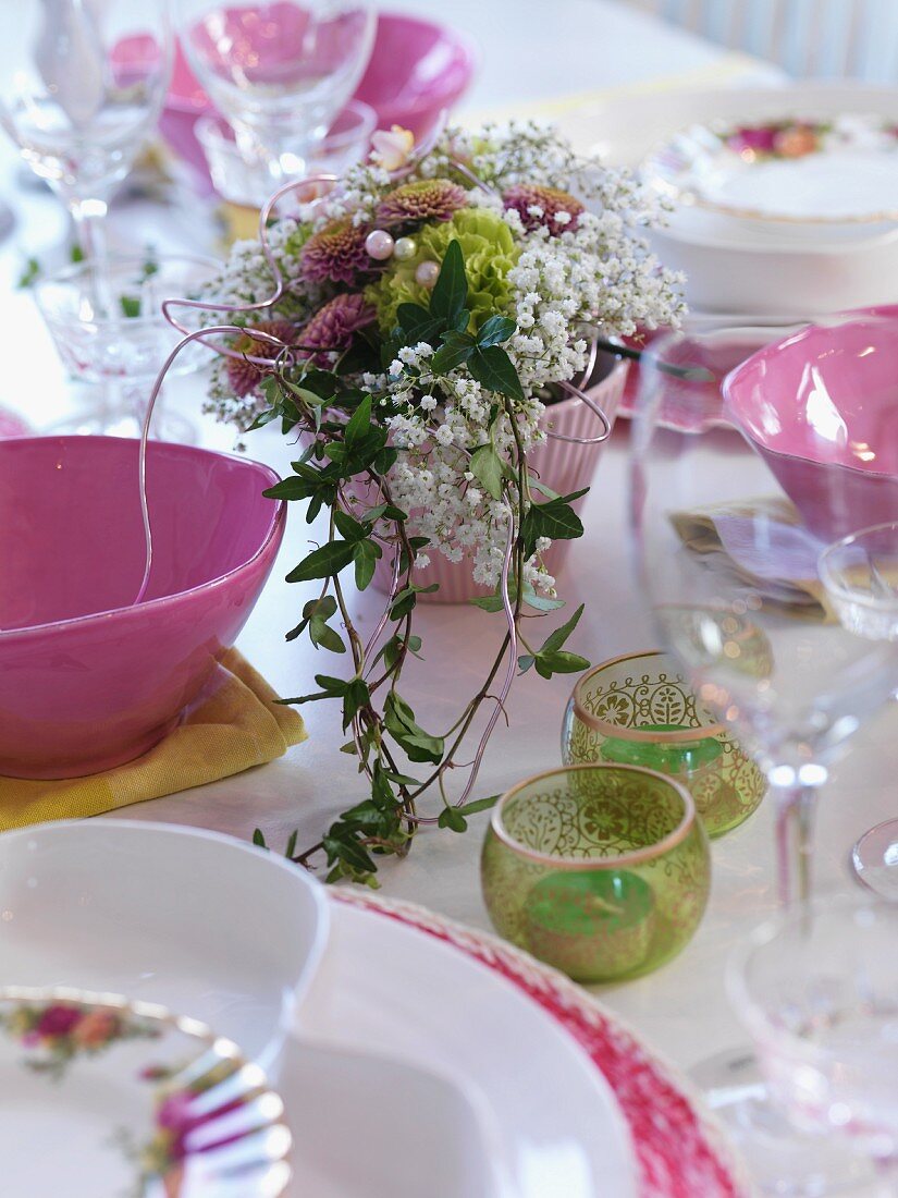 Flower arrangement and green glass tealight holders on festively set table