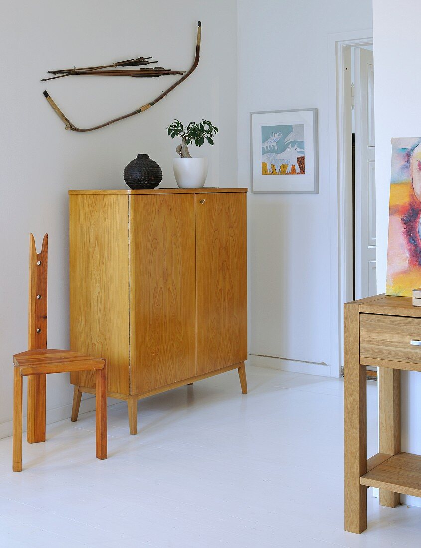 Halbhoher Schrank aus hellem Massivholz im Fiftiesstil und selbstgebauter Stuhl in schlichtem Zimmer