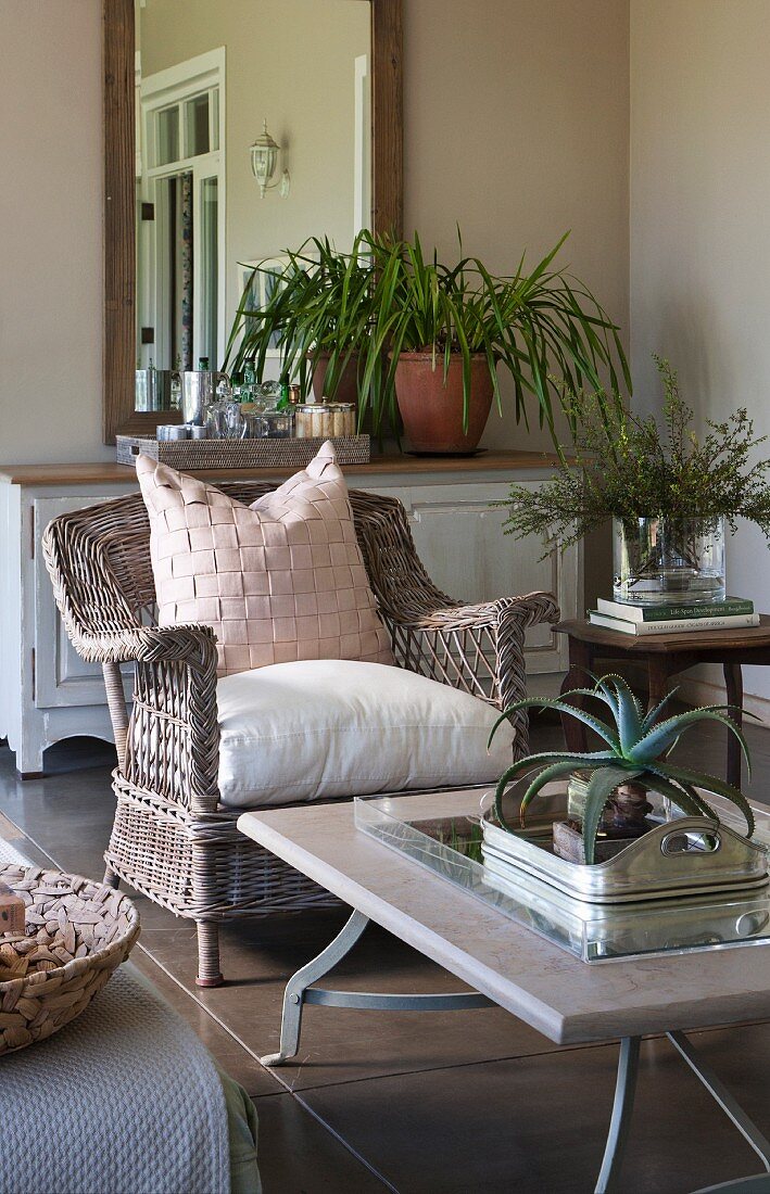 Stone coffee table on metal frame and comfortable rattan armchair on comfortable veranda
