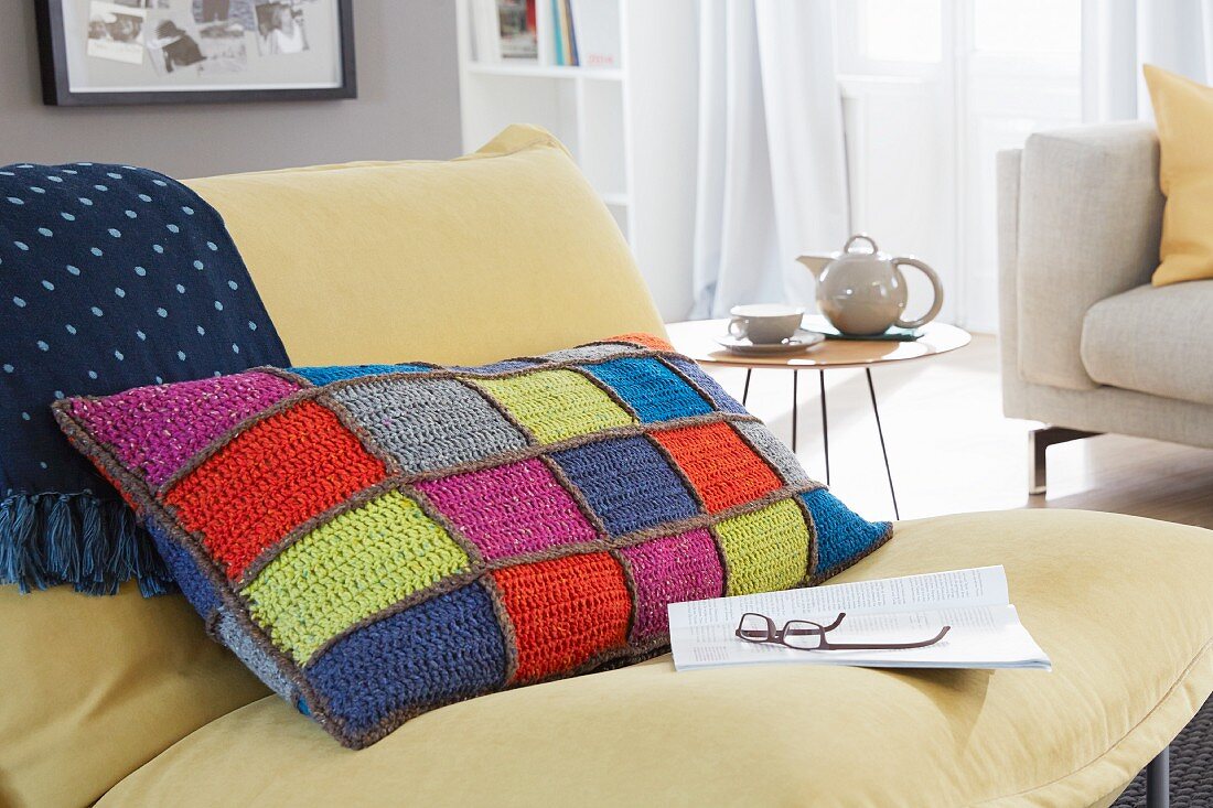 A colourful, homemade, crocheted patchwork cushion cover