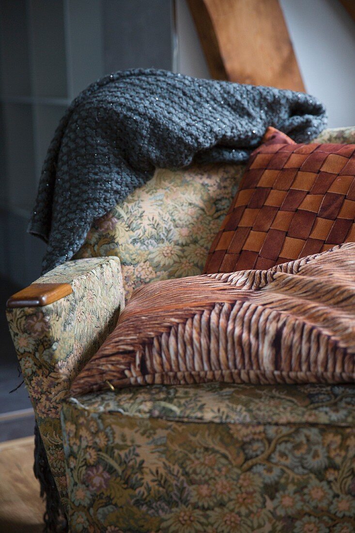Armchair with vintage cover and patterned scatter cushions