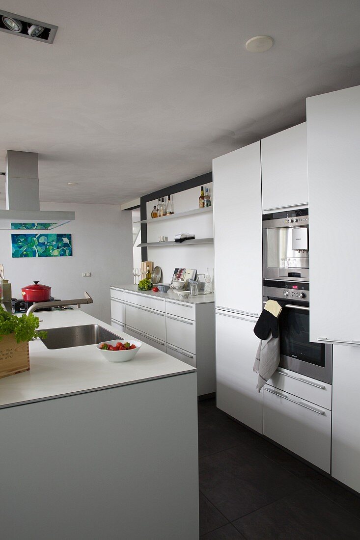 weiße Küche mit Kücheninsel und dunkelgrauem Fliesenboden