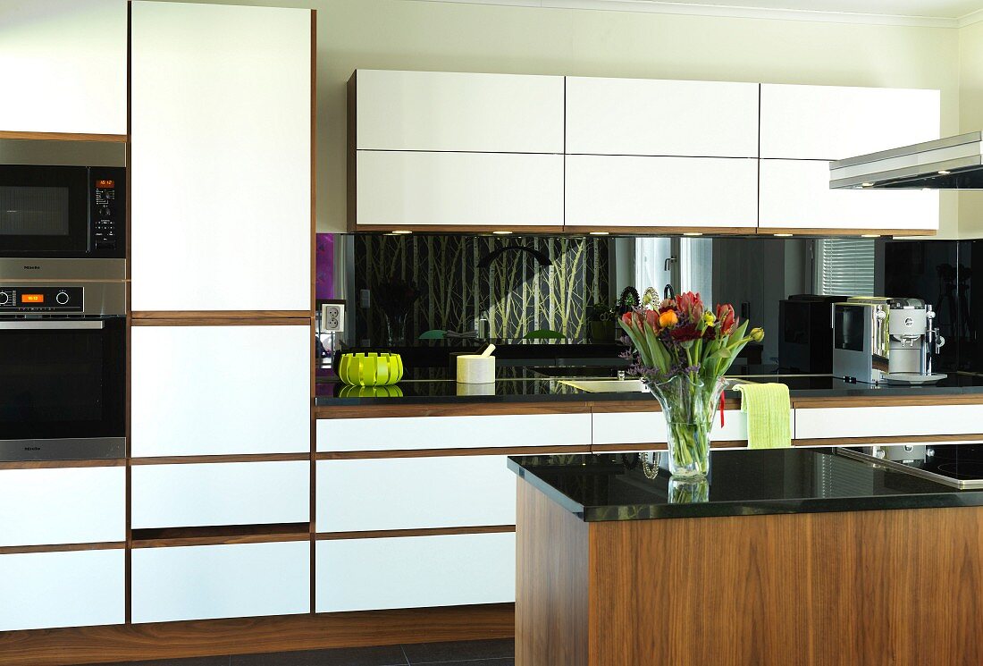 Elegant walnut kitchen with white front panels and black granite worksurface; island counter in foreground