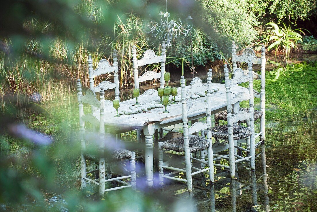 Gedeckter Tisch mit Korbstühlen in Teich stehend