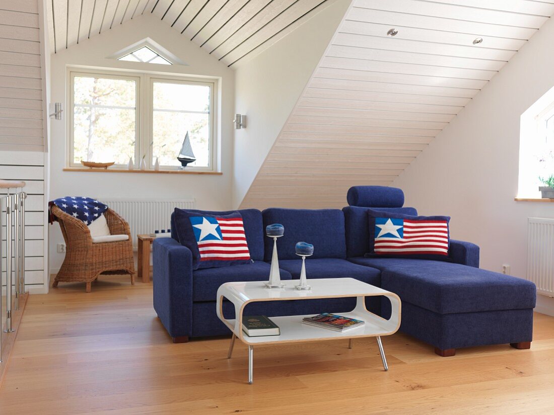 Blue sofa combination with stars and stripes cushions in front of wood-clad sloping ceiling with dormer window