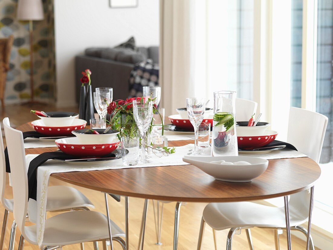 White shell chairs around table festively set with red bowls and black napkins