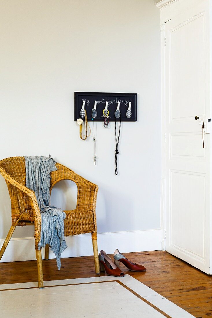 Jewellery rack made from Chinese spoons above wicker chair