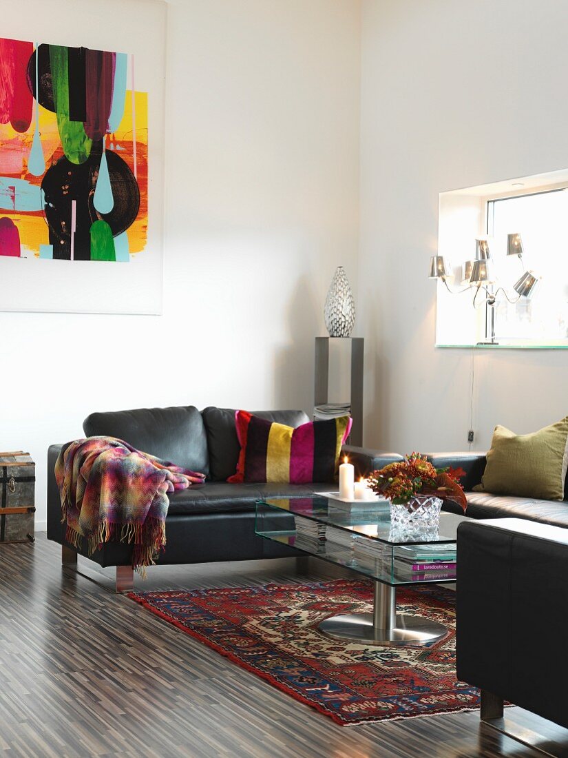 Black leather sofa and glass coffee table on Oriental rug in minimalist interior