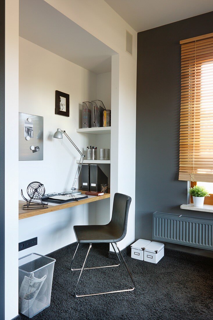 Designerstuhl vor in Nische eingespannter Schreibtischplatte, seitlich grau getönte Wand