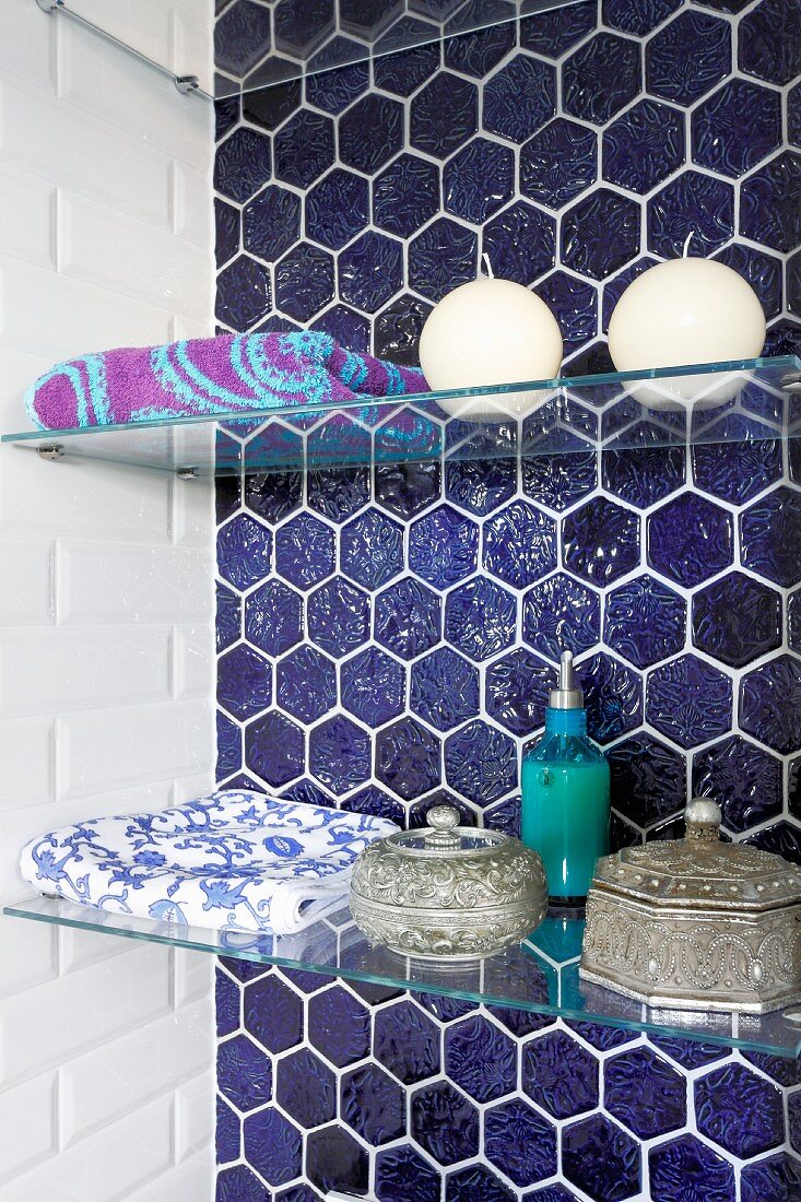 Glasböden in Wandnische mit blauen, wabenförmigen Fliesen, Badutensilien und marokkanische Schatullen