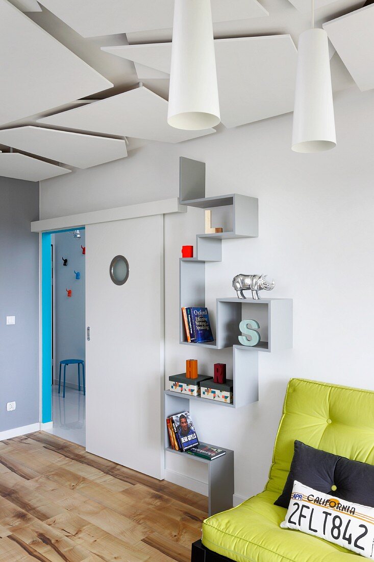 Zig-zag shelves between sliding door with porthole and green futon sofa