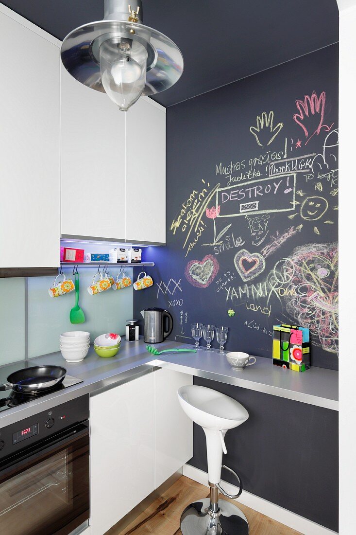 Designer-Barhocker an Thekentisch in Einbauküche vor Tafelwand