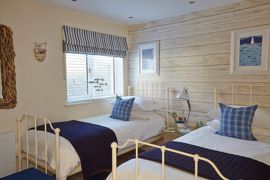 Twin beds in maritime style bedroom with wood paneling and decorative elements