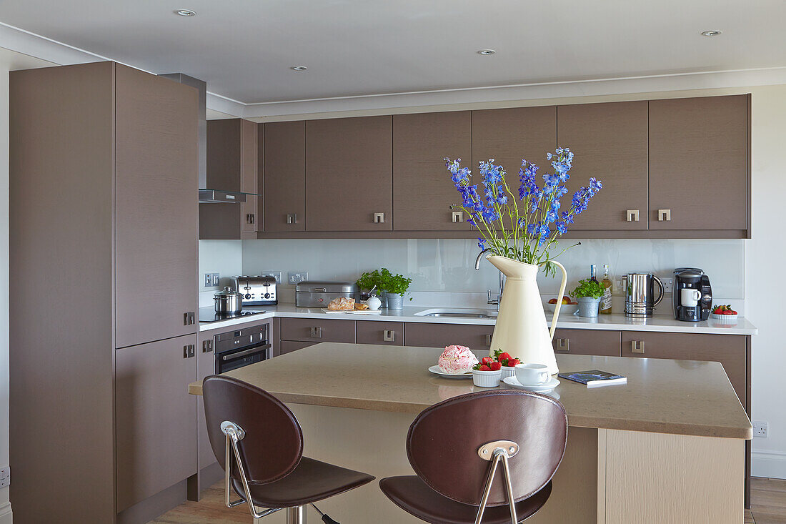 Modern kitchen in brown with blue flowers in a vase on island