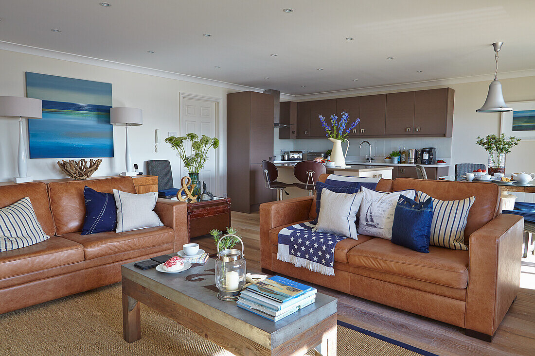 Open-plan living area with leather sofas, kitchen in the background