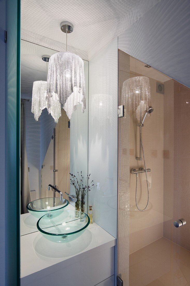 Elegantes Duschbad mit Glaswaschbecken, raumhohem Wandspiegel und Pendelleuchte mit Glitzerstoff