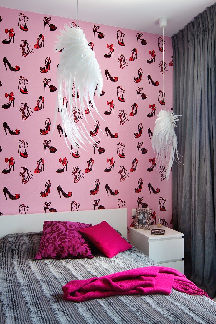 Bedroom in shades of grey and pink with whimsical elements: pendant lamps with white lampshades shaped like wings and shoe-patterned wallpaper