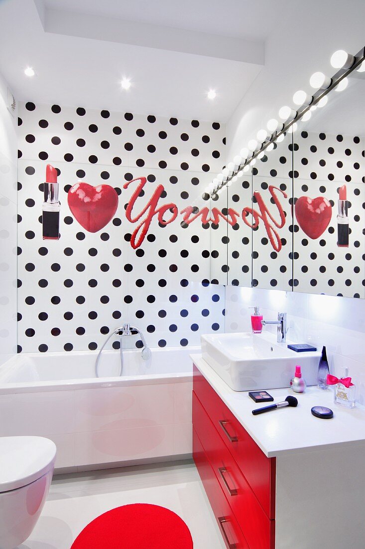 Herz und Lippenstift Motive auf schwarz gepunkteter Badezimmerwand in modernem, weißem Bad mit roten Akzenten