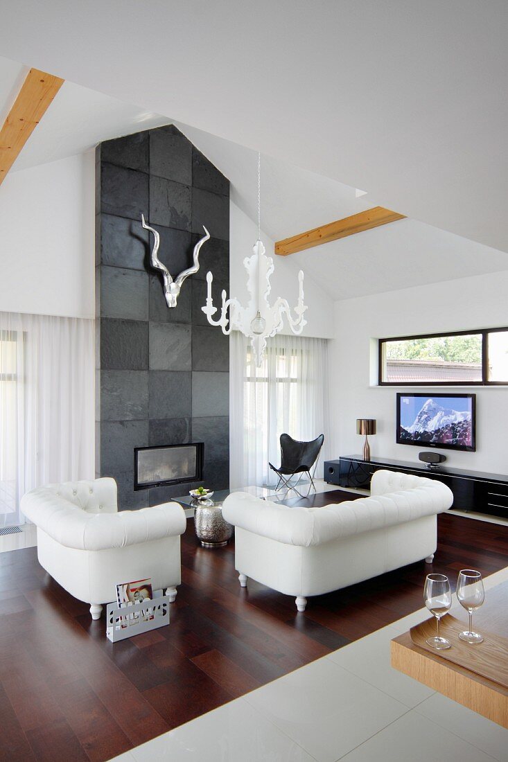 Elegante Sofagarnitur aus weißem Leder vor Kamin, integriert in Wand mit Schieferfliesen