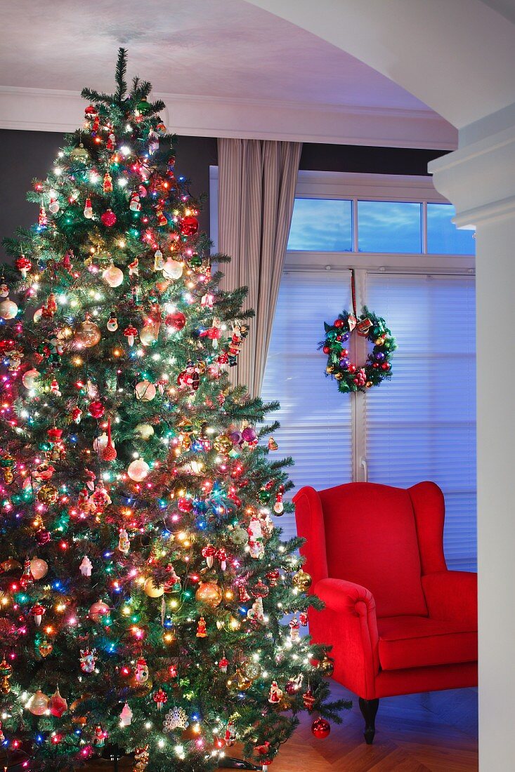 Red armchair next to magnificently decorated Christmas tree in living room