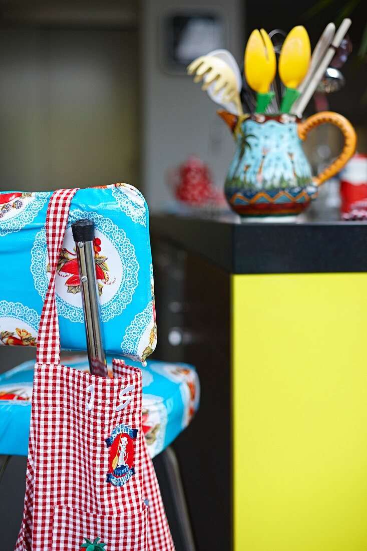Rotweiss karierte Stofftasche an 50er Jahre Küchenstuhl mit kitschigem Spitzendeckchen-Motiv