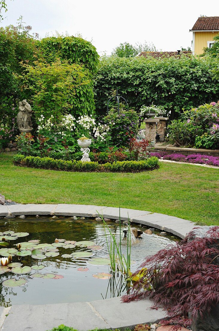Runder Teich mit Seerosen in sommerlichem Garten