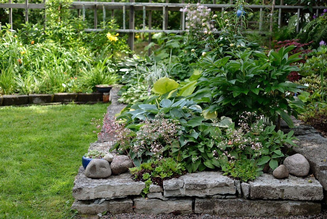 Hochbeet mit Natursteineinfassung in sommerlichem Garten