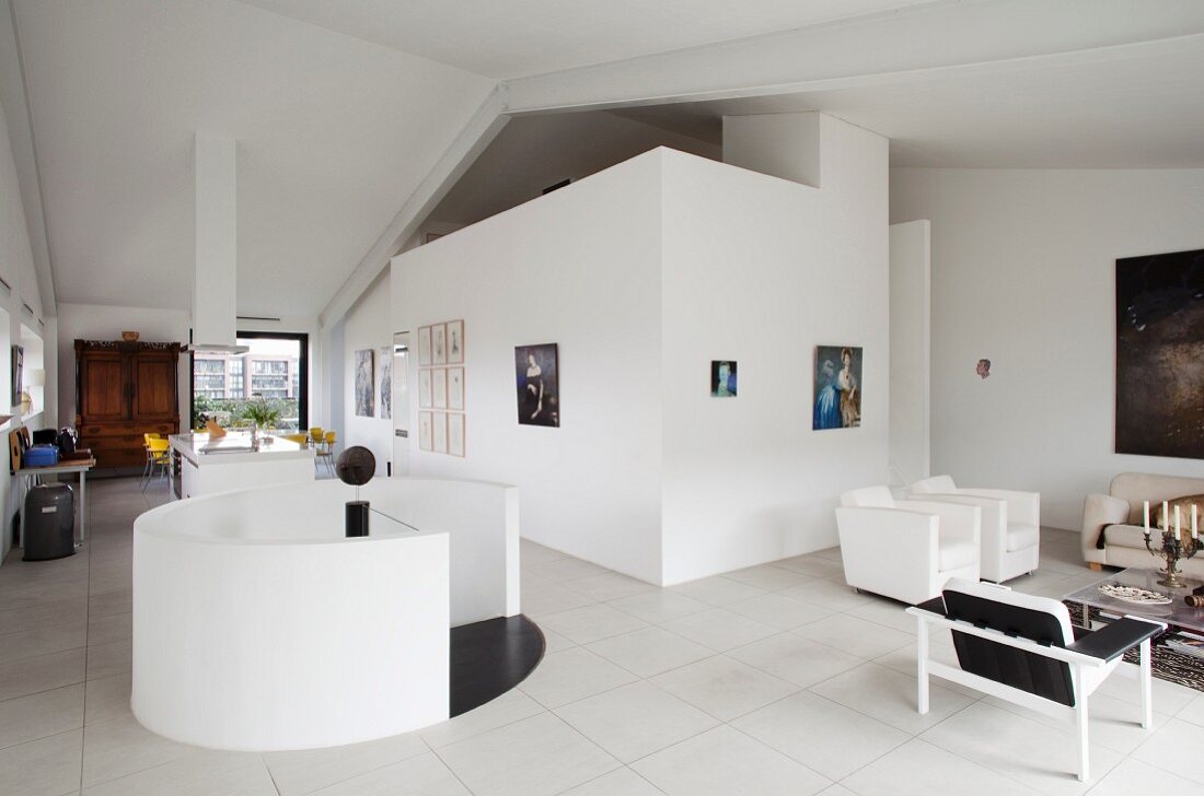 Moderne Loftwohnung, runder Treppenabgang mit weisser Brüstungsmauer, seitlich Loungebereich mit minimalistischem Flair