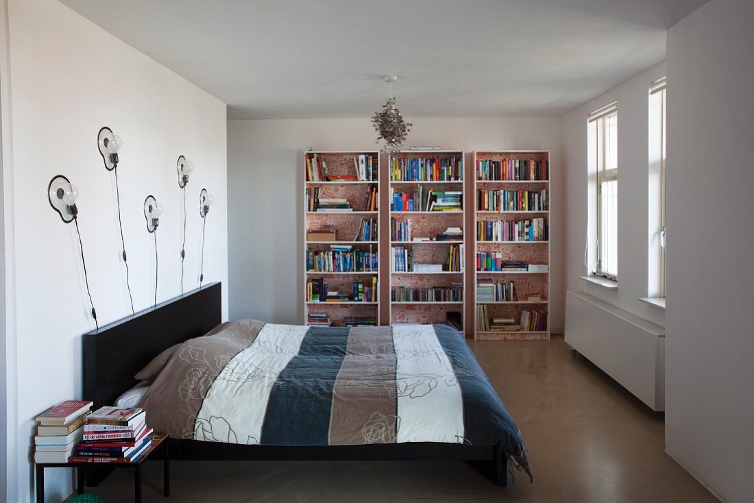 Schlafbereich mit Designerwandleuchten und Bücherregal