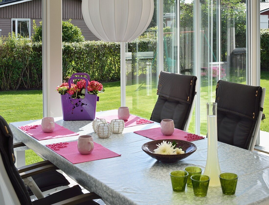 Table in conservatory with view into sunny garden
