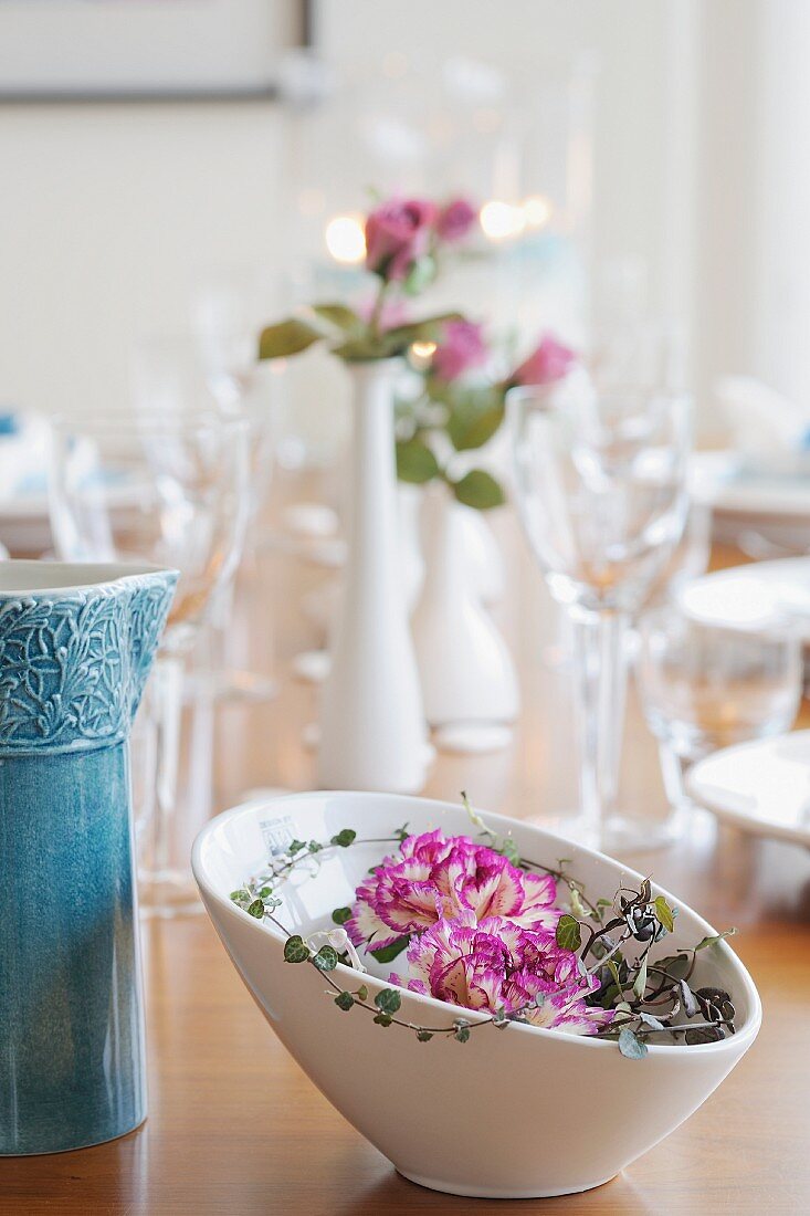 weiße Porzellanschale mit Blüten auf gedecktem Tisch