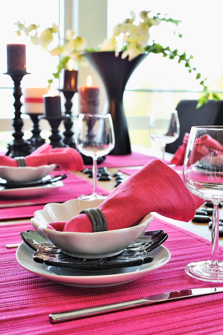 Festlich gedeckter Tisch mit pinkfarbener Stoffserviette auf Gedeck und Tischset
