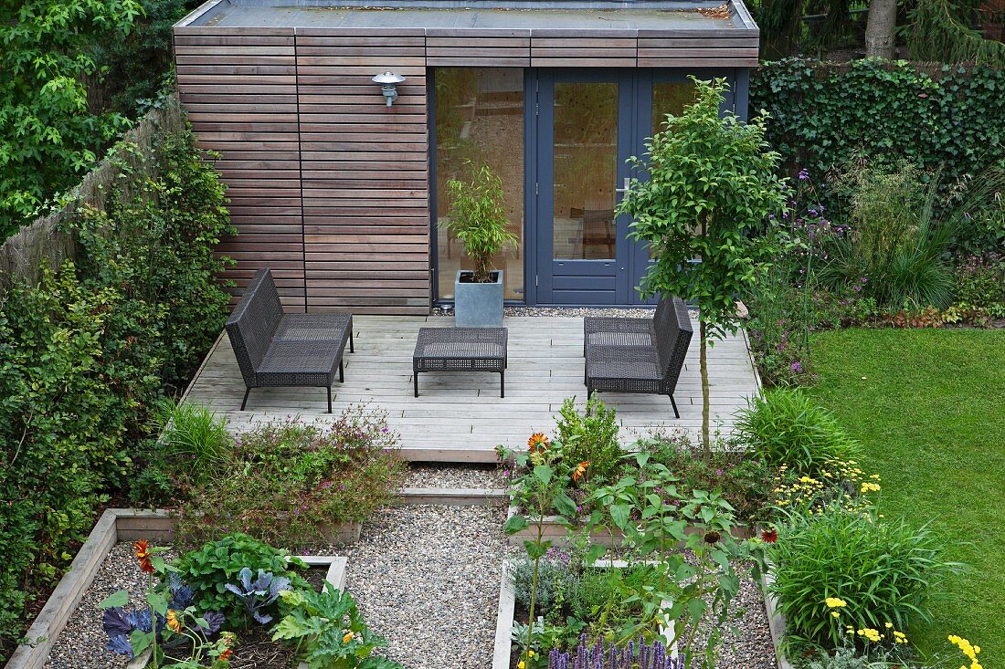 Raised beds in front of outdoor furniture on modern terrace with summer house