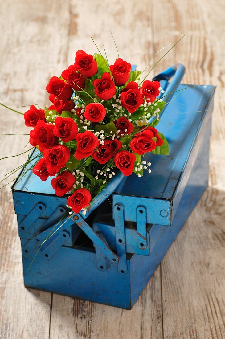 Roter Rosenstrauss in blauem Werkzeugkasten