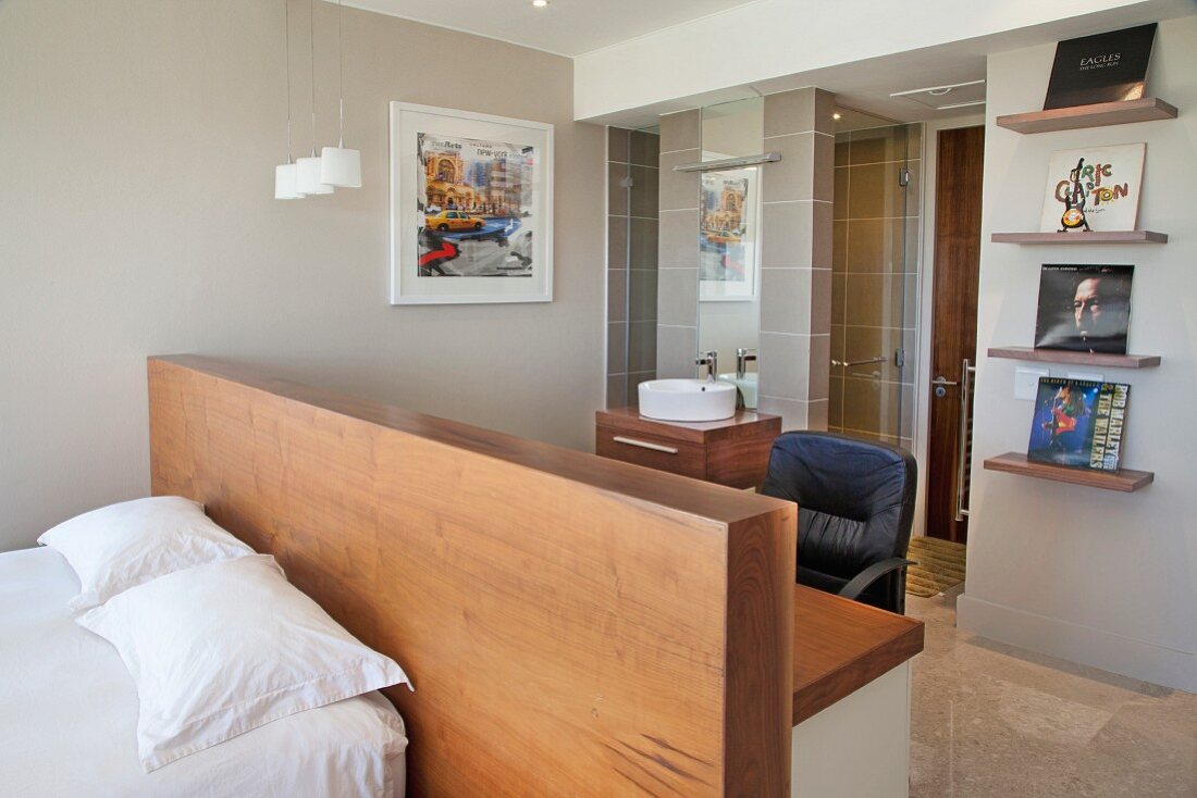 Double bed against half-height partition with desk in front of ensuite bathroom