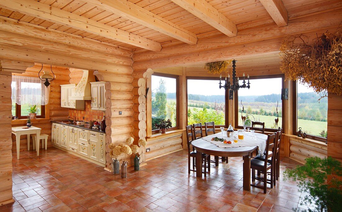 Grossräumiges Wohnzimmer mit Essplatz im Erkerbereich und offene Küche in Massivholzhaus