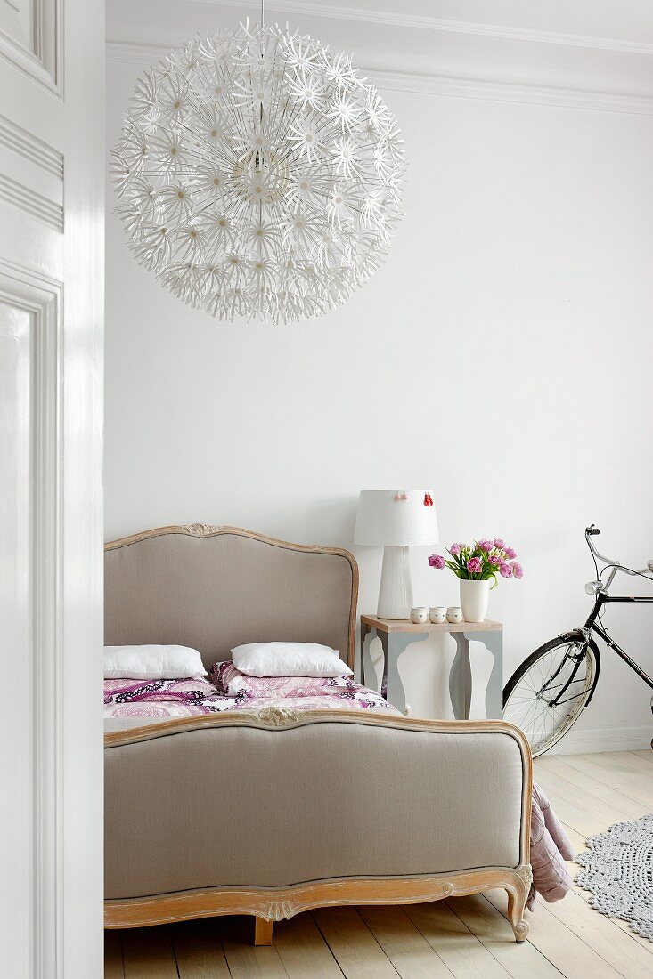 Double bed, designer lamp on bedside table and bicycle