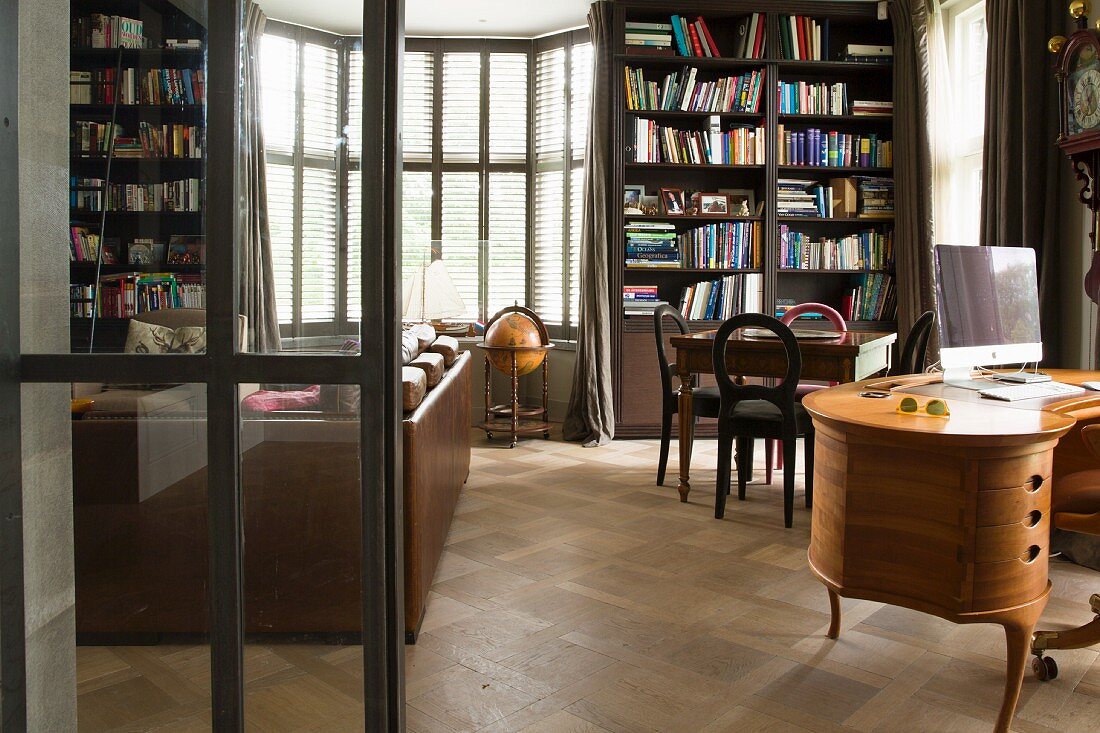 View of desk and bookcase through steel-framed door with glass panels