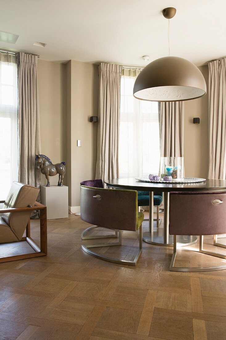 Designerstühle um runden Tisch in Zimmer in Beigetönen