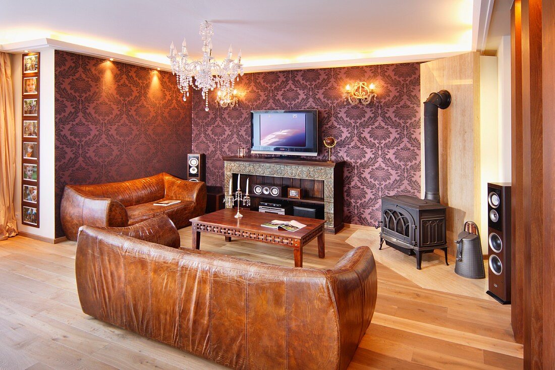 Braune Vintage Ledersofa in traditionellem Wohnzimmer mit Kaminofen, teilweise tapezierte Wände mit Ornamentmuster auf violettem Grund