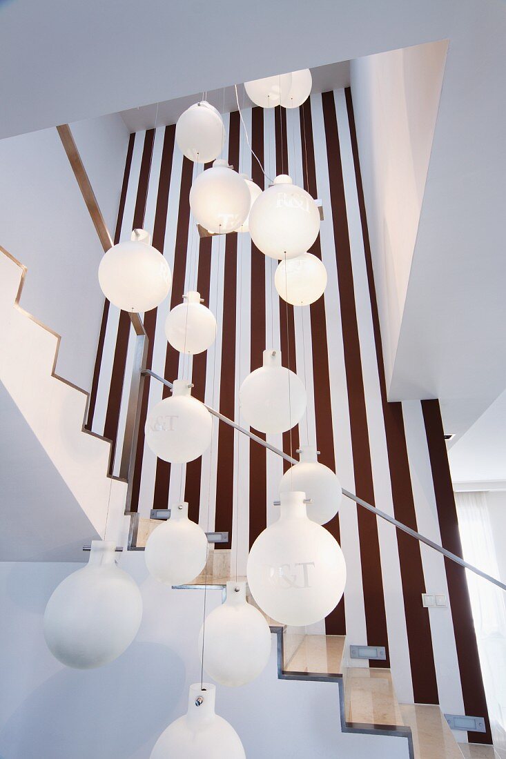 White spherical pendant lamps hanging at different heights in open-plan stairwell